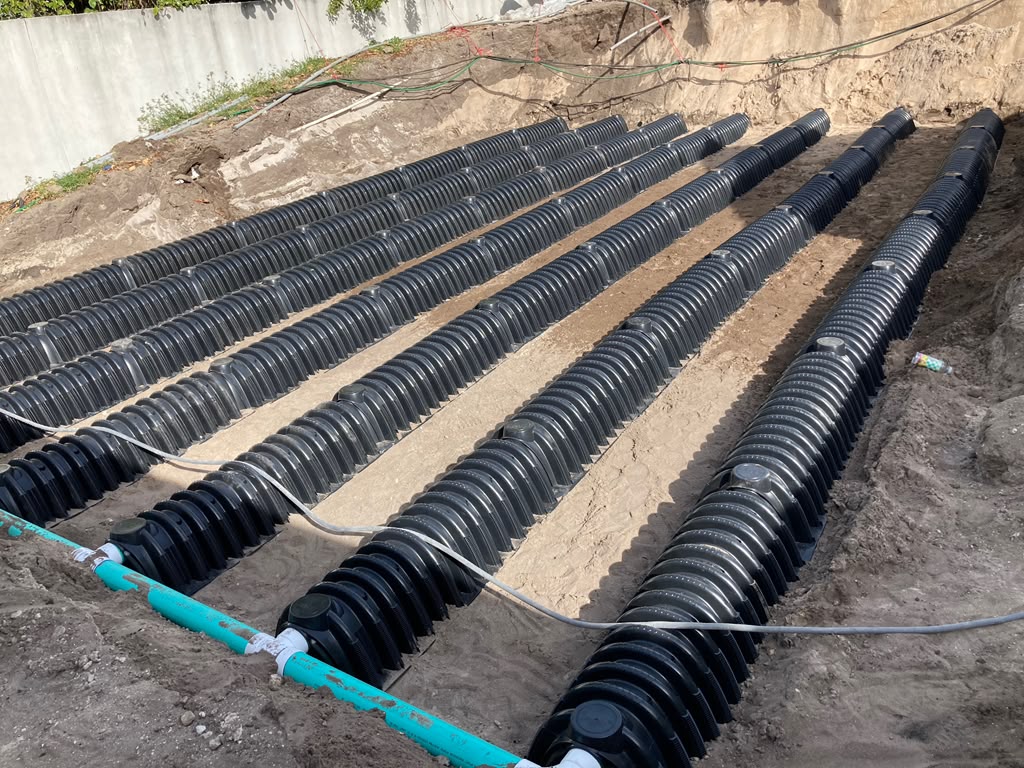 Many parallel black chamber rows in a large excavated area