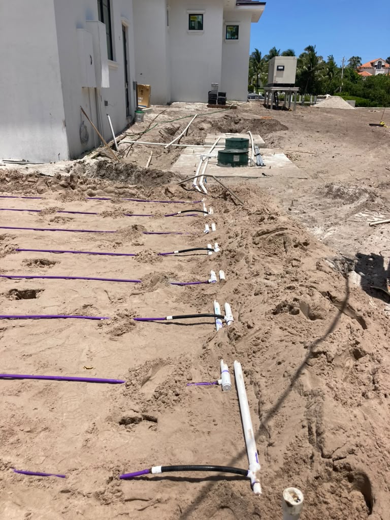 Exposed white PVC piping and purple lateral lines in sand